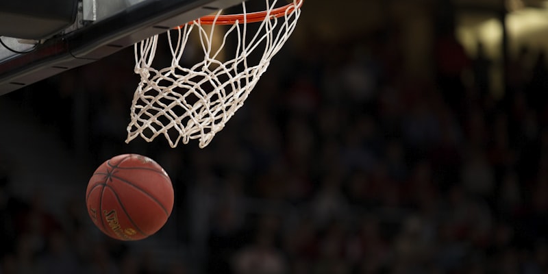 Basketball player executing a slam dunk during an intense game
